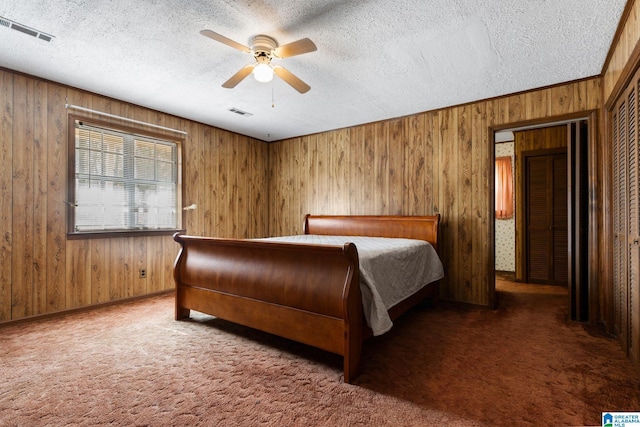 unfurnished bedroom featuring ceiling fan, carpet floors, wooden walls, and a textured ceiling