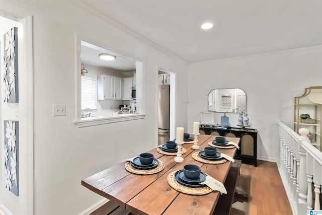 dining area with ornamental molding, sink, and hardwood / wood-style floors