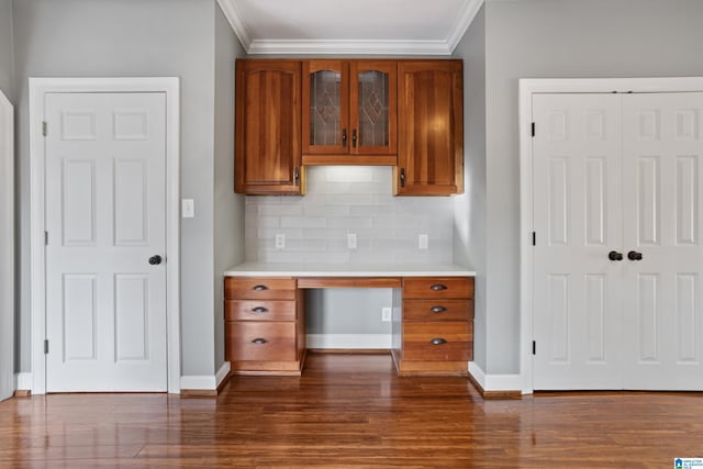 kitchen with dark hardwood / wood-style flooring, decorative backsplash, built in desk, and ornamental molding