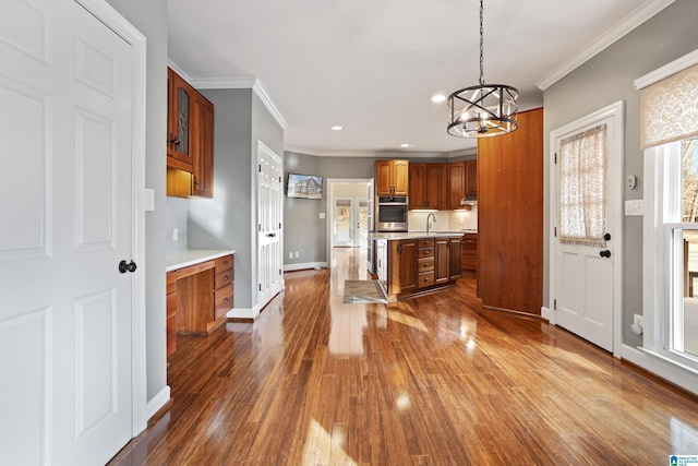 kitchen featuring sink, crown molding, stainless steel oven, hanging light fixtures, and dark hardwood / wood-style floors