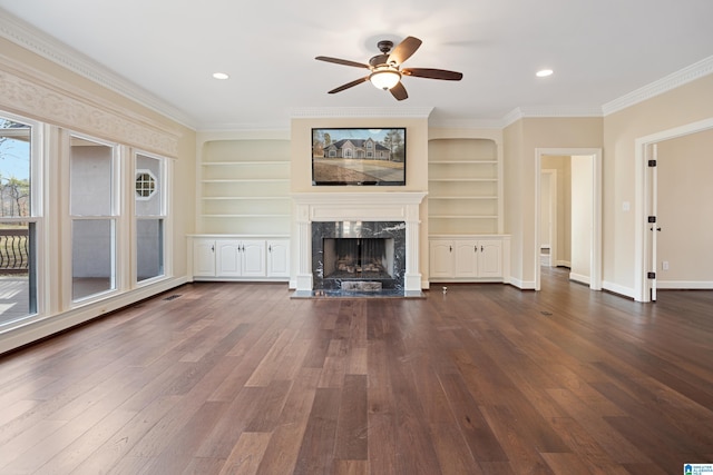 unfurnished living room featuring dark wood-type flooring, ornamental molding, built in features, ceiling fan, and a high end fireplace