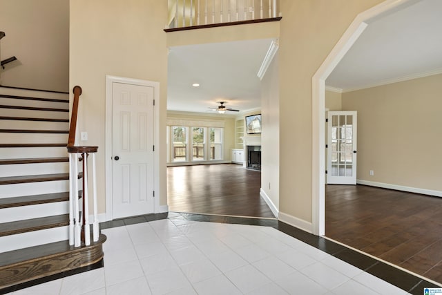 entrance foyer featuring crown molding, light hardwood / wood-style flooring, ceiling fan, and a high ceiling