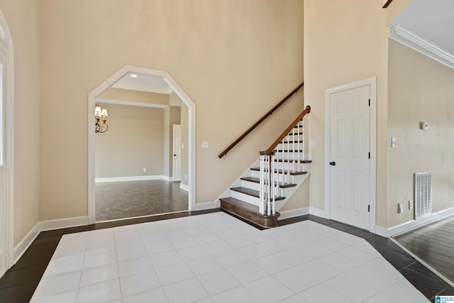 foyer featuring a high ceiling, ornamental molding, tile patterned floors, and an inviting chandelier