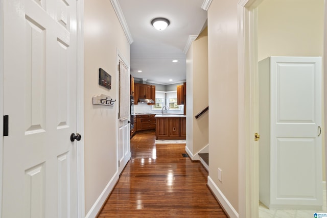 hallway with dark wood-type flooring, ornamental molding, and sink