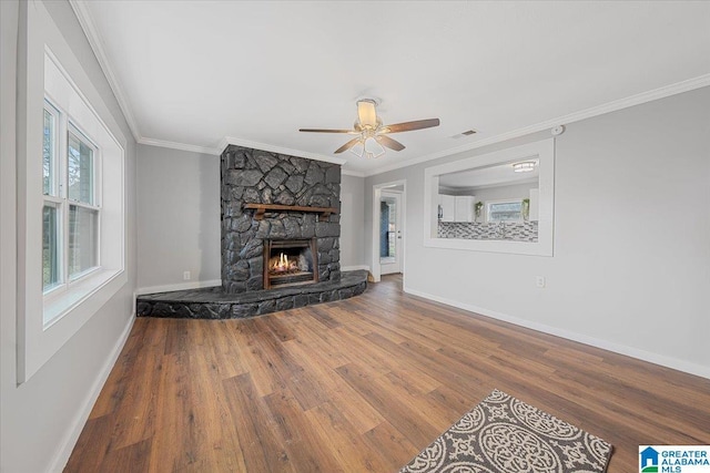 living room with hardwood / wood-style flooring, crown molding, a stone fireplace, and ceiling fan