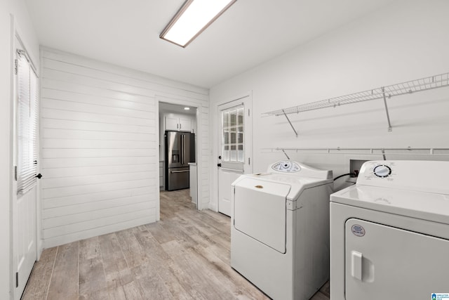 washroom with a wealth of natural light, washing machine and clothes dryer, and light wood-type flooring