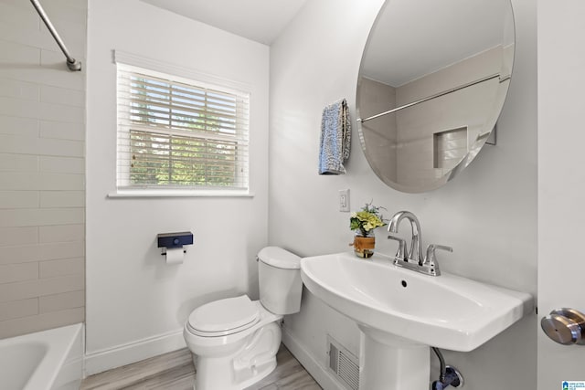 full bathroom with washtub / shower combination, toilet, sink, and hardwood / wood-style floors