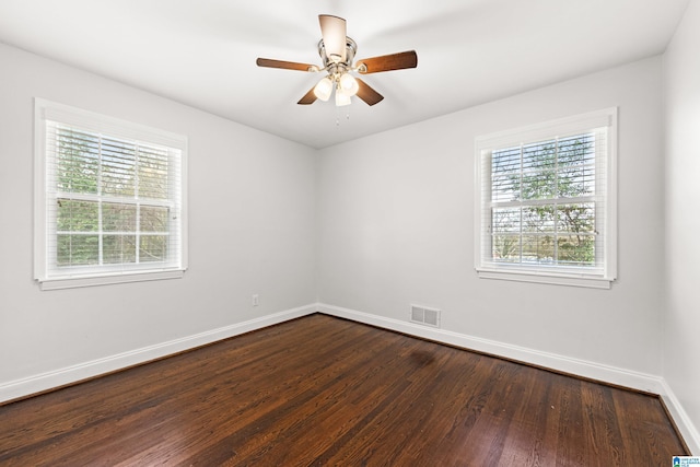 spare room with dark wood-type flooring, ceiling fan, and a wealth of natural light