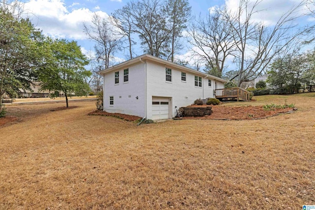 view of home's exterior featuring a wooden deck, a garage, and a yard