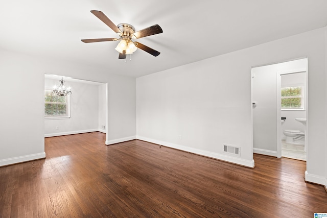 unfurnished room featuring a healthy amount of sunlight, dark hardwood / wood-style floors, and ceiling fan with notable chandelier