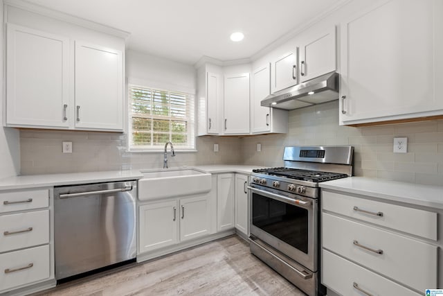 kitchen with appliances with stainless steel finishes, sink, decorative backsplash, and white cabinets