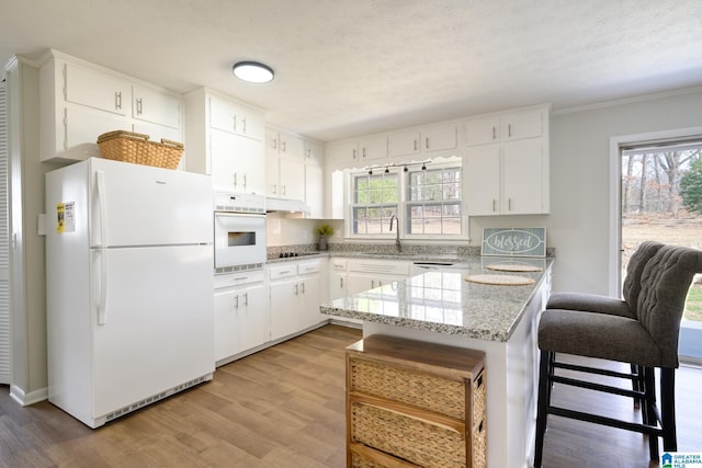 kitchen featuring sink, white cabinets, light stone countertops, white appliances, and light hardwood / wood-style flooring