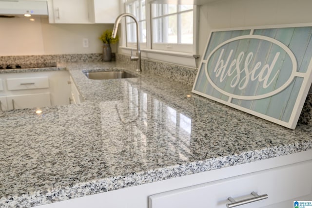 details with extractor fan, sink, white cabinets, black electric stovetop, and light stone counters