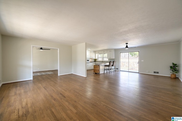 unfurnished living room featuring dark hardwood / wood-style floors and ceiling fan