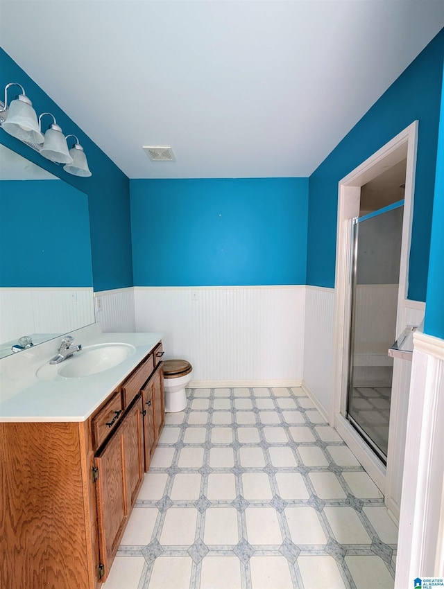 bathroom featuring visible vents, toilet, wainscoting, a shower stall, and tile patterned floors