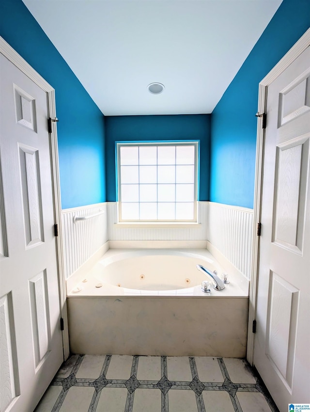 full bath featuring a wainscoted wall and a tub with jets