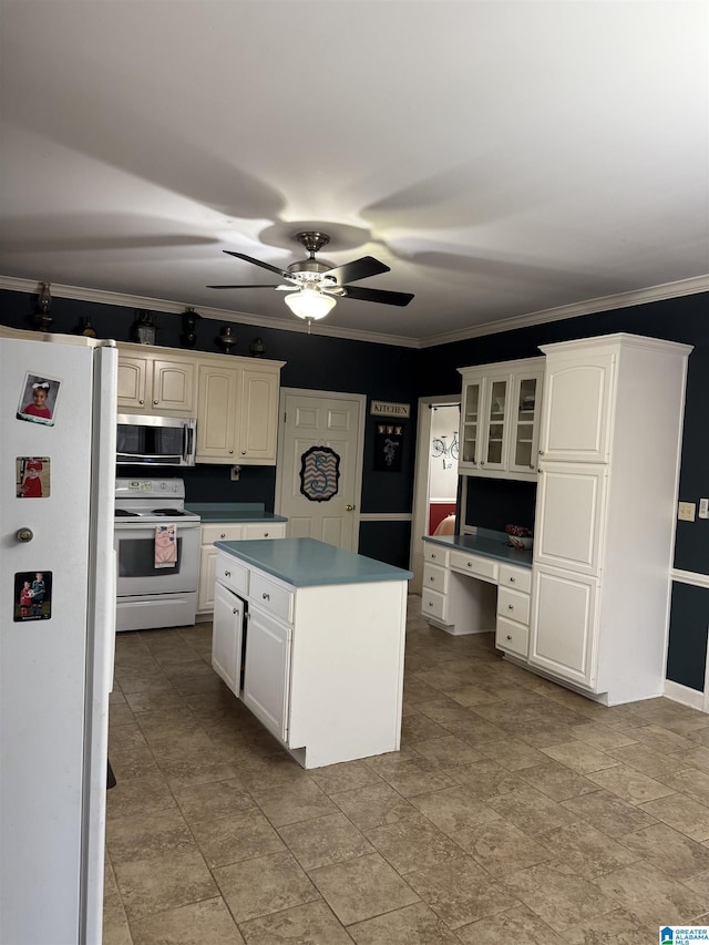 kitchen with crown molding, white appliances, a center island, built in desk, and white cabinets