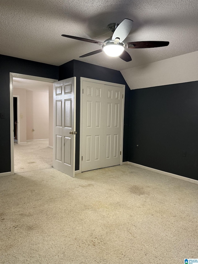 unfurnished bedroom with vaulted ceiling, carpet, ceiling fan, a textured ceiling, and a closet