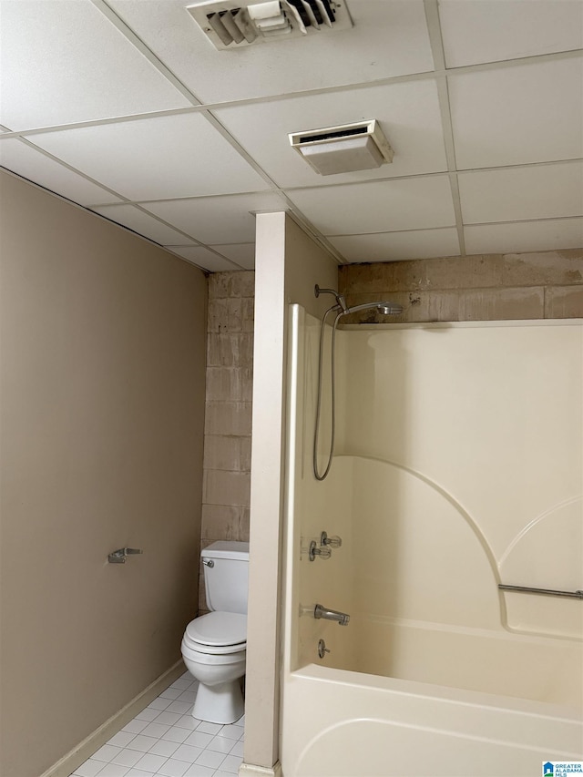 bathroom with tub / shower combination, a drop ceiling, tile patterned floors, and toilet