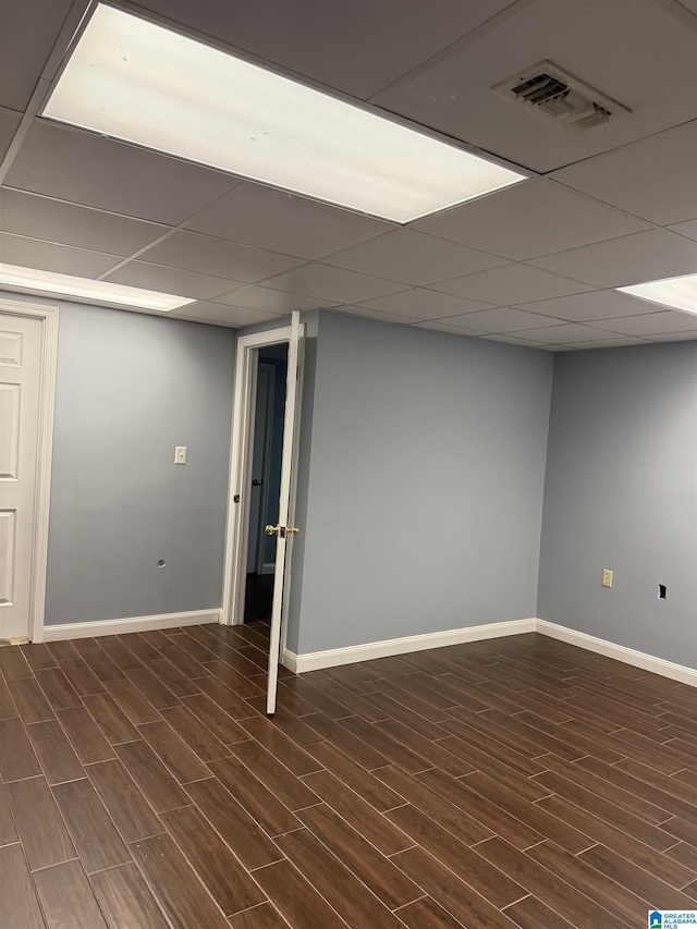 basement featuring dark wood-type flooring and a paneled ceiling