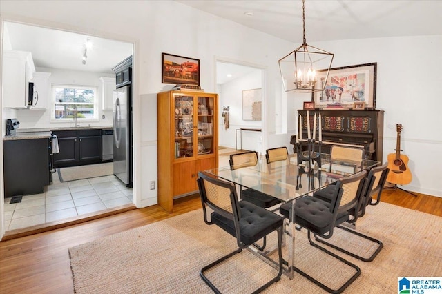 dining area with light wood-type flooring and an inviting chandelier