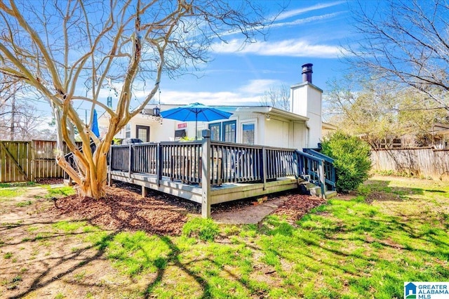 rear view of property featuring a chimney, fence, and a deck