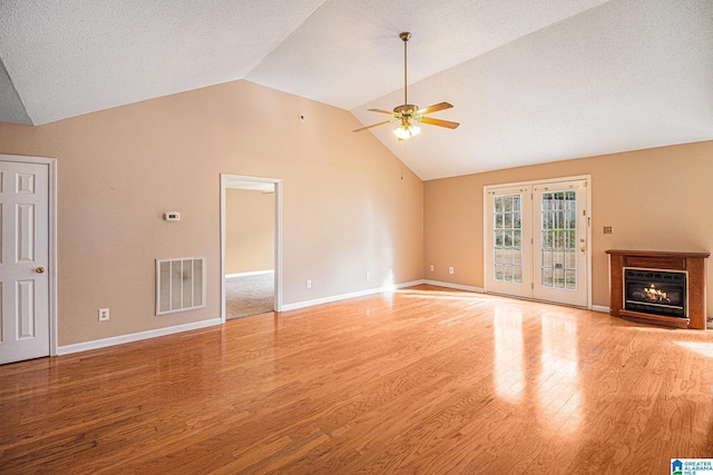 unfurnished living room with lofted ceiling, a textured ceiling, ceiling fan, and light wood-type flooring