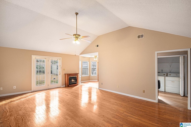 unfurnished living room with vaulted ceiling, ceiling fan, independent washer and dryer, light hardwood / wood-style floors, and a textured ceiling