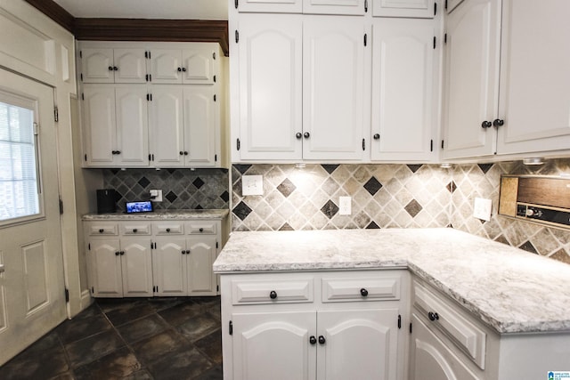 kitchen featuring light stone countertops, decorative backsplash, and white cabinets