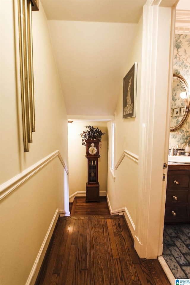 hallway with dark wood-type flooring, lofted ceiling, and sink