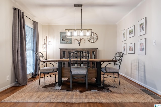 dining space with hardwood / wood-style floors and crown molding