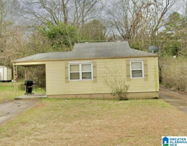 view of front of property with a carport, a front yard, and a storage shed