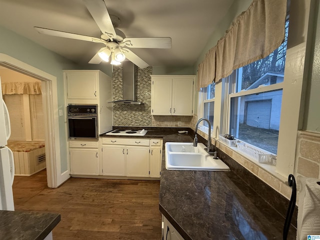 kitchen featuring white cabinetry, wall chimney range hood, white appliances, and sink