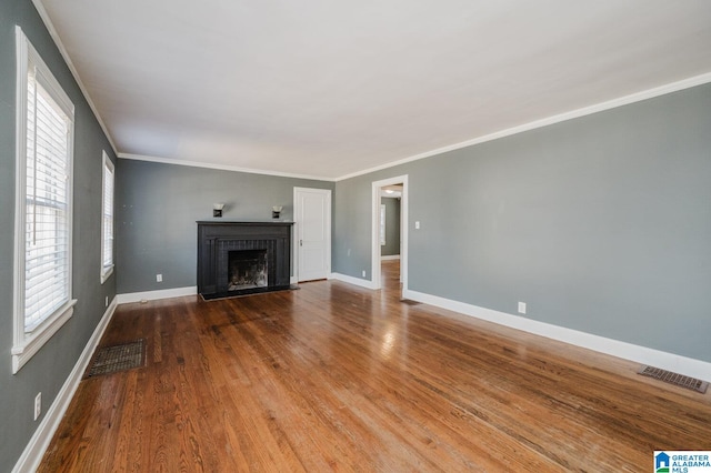 unfurnished living room with a brick fireplace, wood-type flooring, and ornamental molding