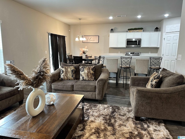 living room with dark wood-type flooring and a chandelier