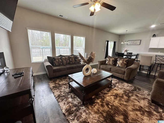 living room with dark wood-type flooring and ceiling fan