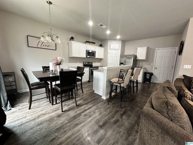 kitchen with white cabinetry, appliances with stainless steel finishes, dark hardwood / wood-style floors, and hanging light fixtures