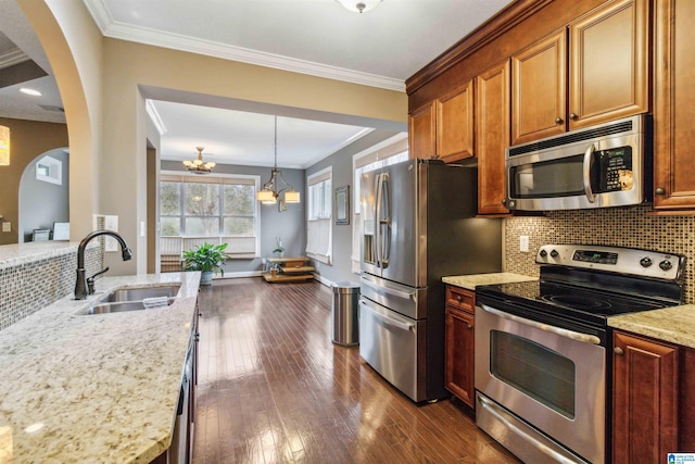 kitchen with sink, appliances with stainless steel finishes, light stone counters, ornamental molding, and decorative backsplash