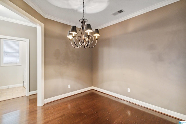 spare room with crown molding, hardwood / wood-style flooring, and an inviting chandelier