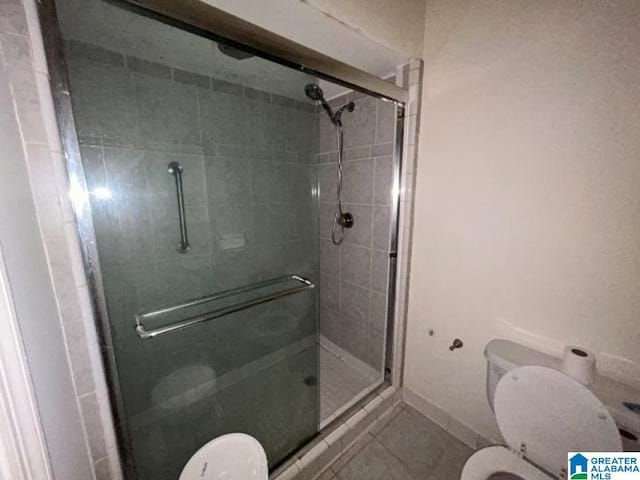 bathroom with tile patterned flooring, an enclosed shower, and toilet