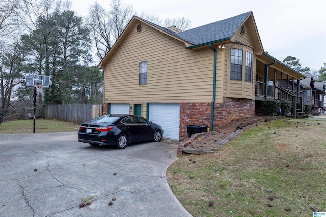 view of side of property with brick siding, a shingled roof, an attached garage, fence, and driveway