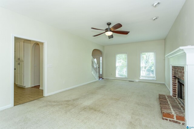 unfurnished living room with ceiling fan, light carpet, and a fireplace