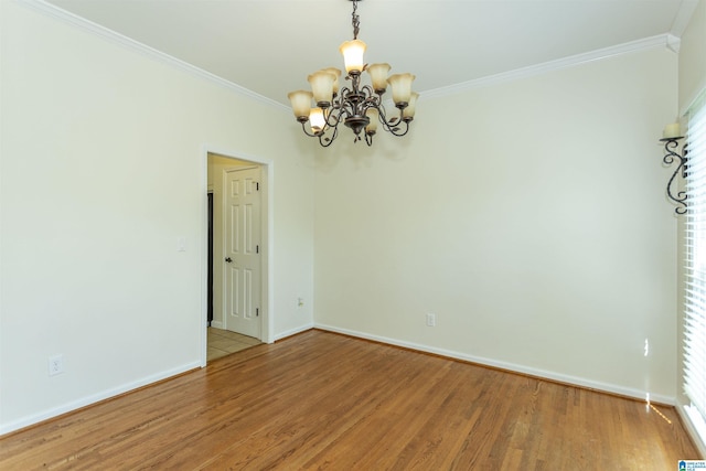 empty room with hardwood / wood-style flooring, ornamental molding, and an inviting chandelier