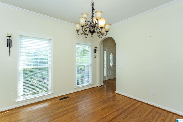 empty room featuring crown molding, wood-type flooring, and a chandelier