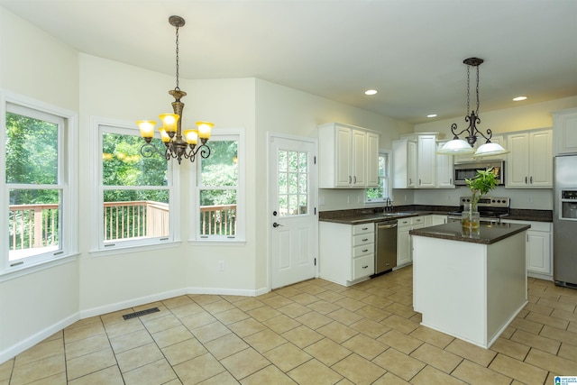 kitchen with hanging light fixtures, a kitchen island, appliances with stainless steel finishes, and white cabinets