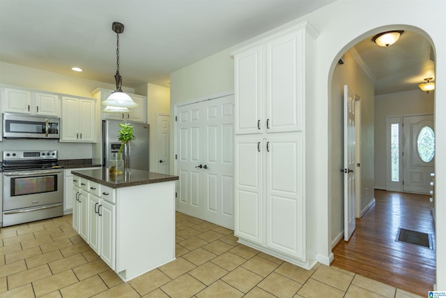 kitchen with white cabinetry, stainless steel appliances, a center island, and hanging light fixtures