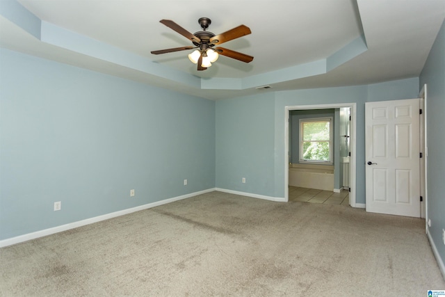 carpeted spare room featuring ceiling fan and a tray ceiling