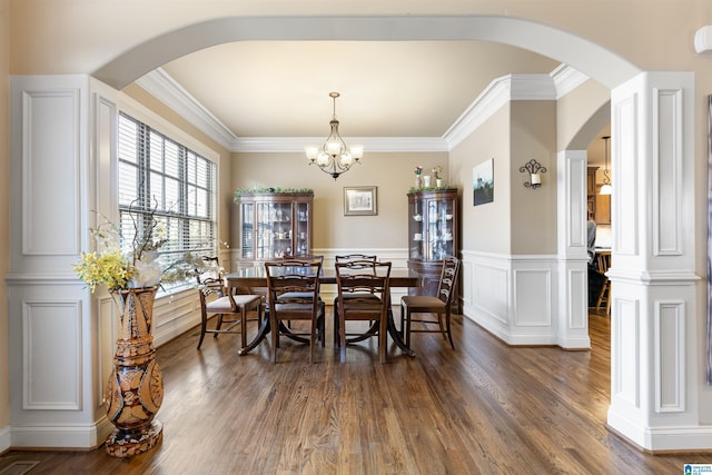 dining space featuring dark wood-type flooring, crown molding, and a notable chandelier