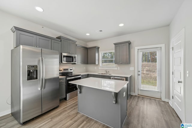 kitchen with sink, stainless steel appliances, a center island, and light wood-type flooring