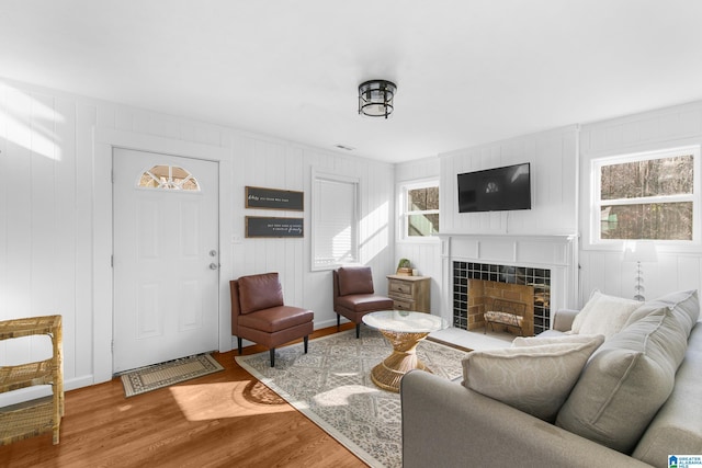 living room featuring hardwood / wood-style flooring, a tiled fireplace, and a wealth of natural light